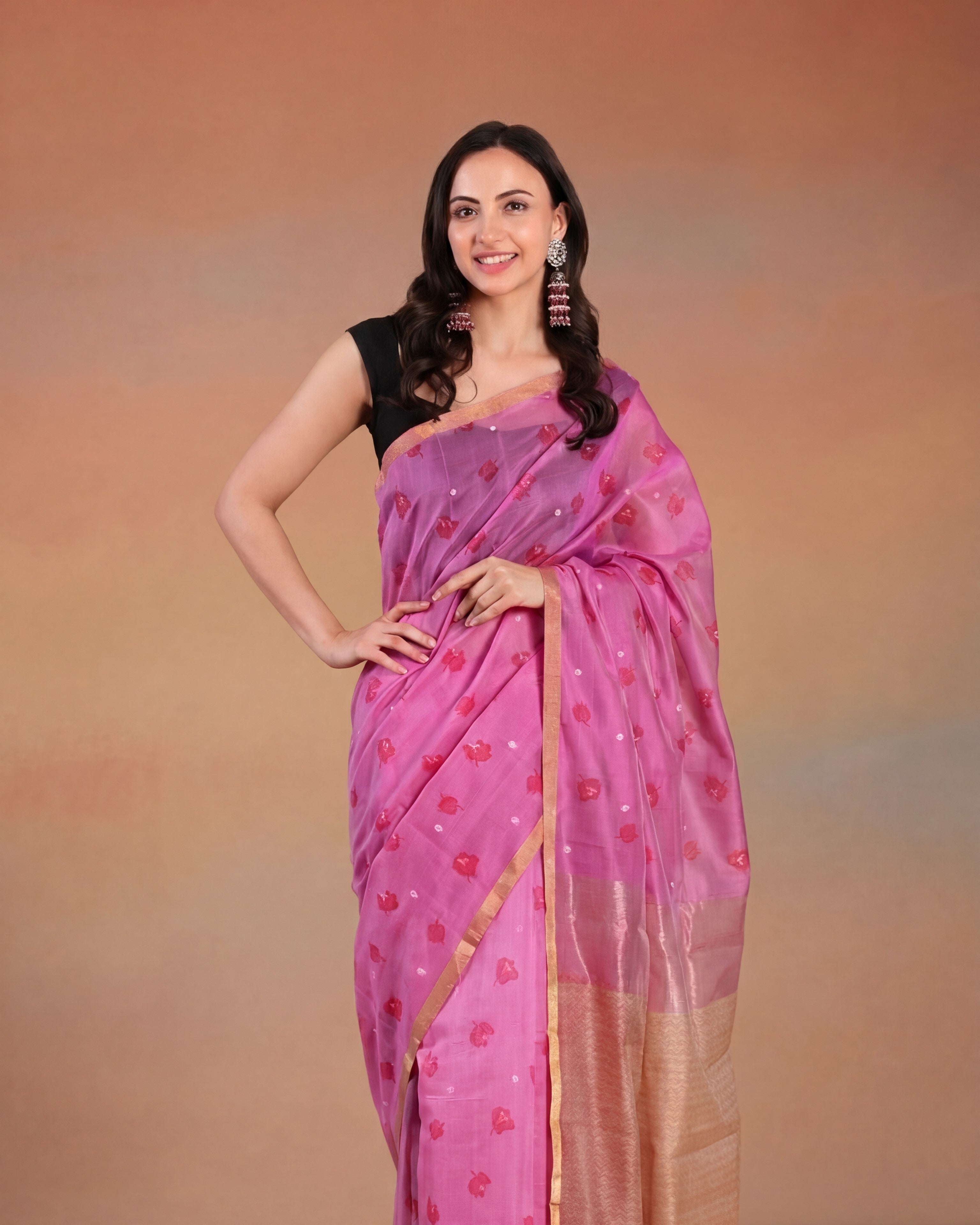 Woman wearing a pink chanderi printed saree with a black blouse against a brown background