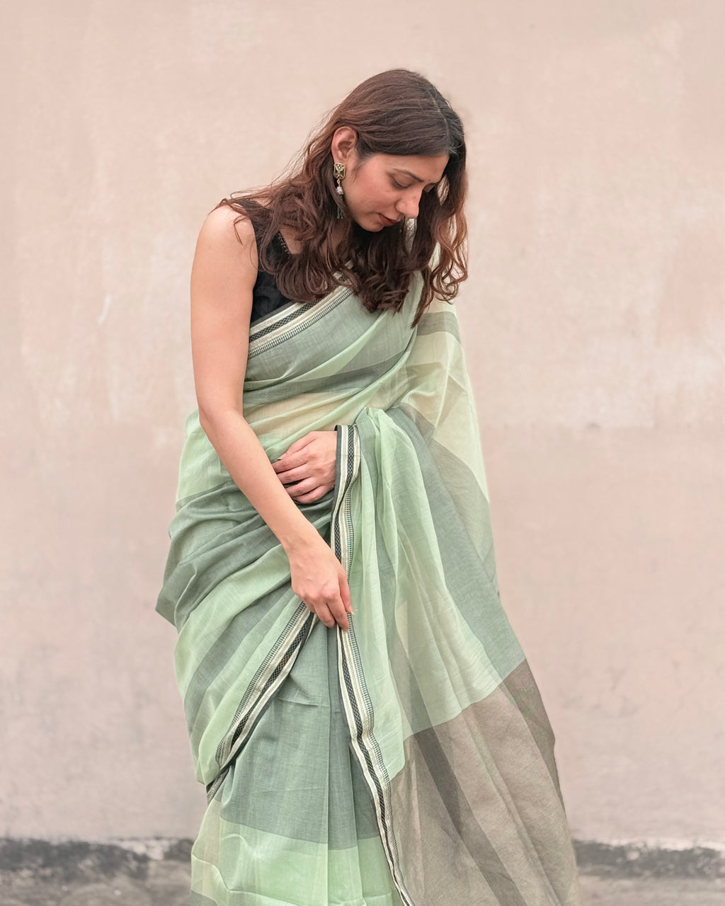Woman wearing a mint green maheshwari silk cotton saree with a subtle pattern against a plain background