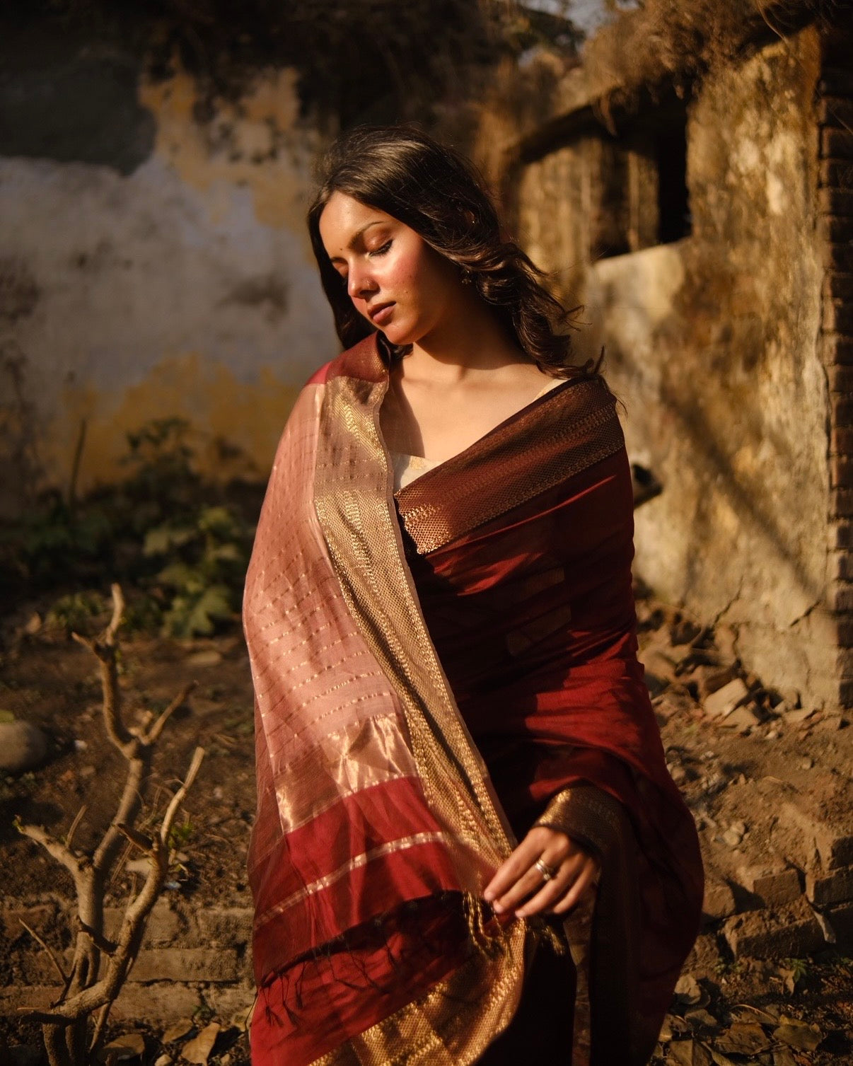 Woman in a traditional maheshwari silk cotton  saree standing in front of an old building.