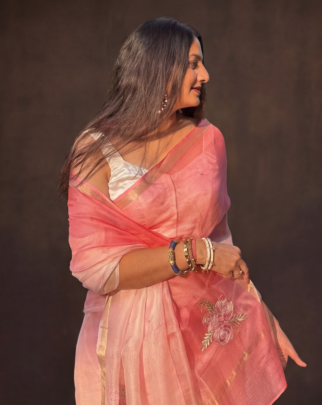 Woman wearing a pink ombre kota silk saree with a dark background